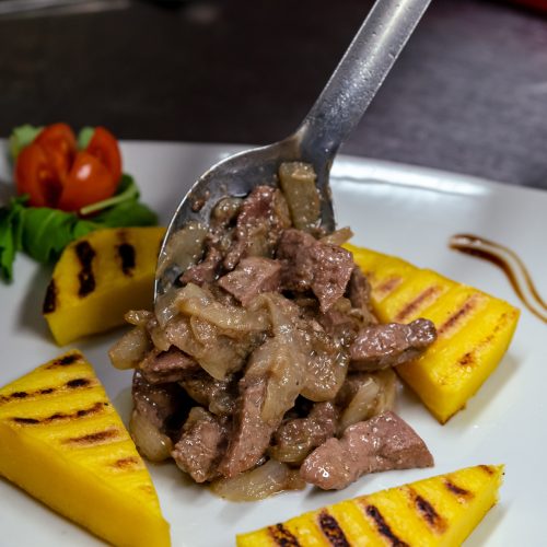 venetian liver recepy ,corn bread ,pork liver ,onions beautiful placed on a white plate